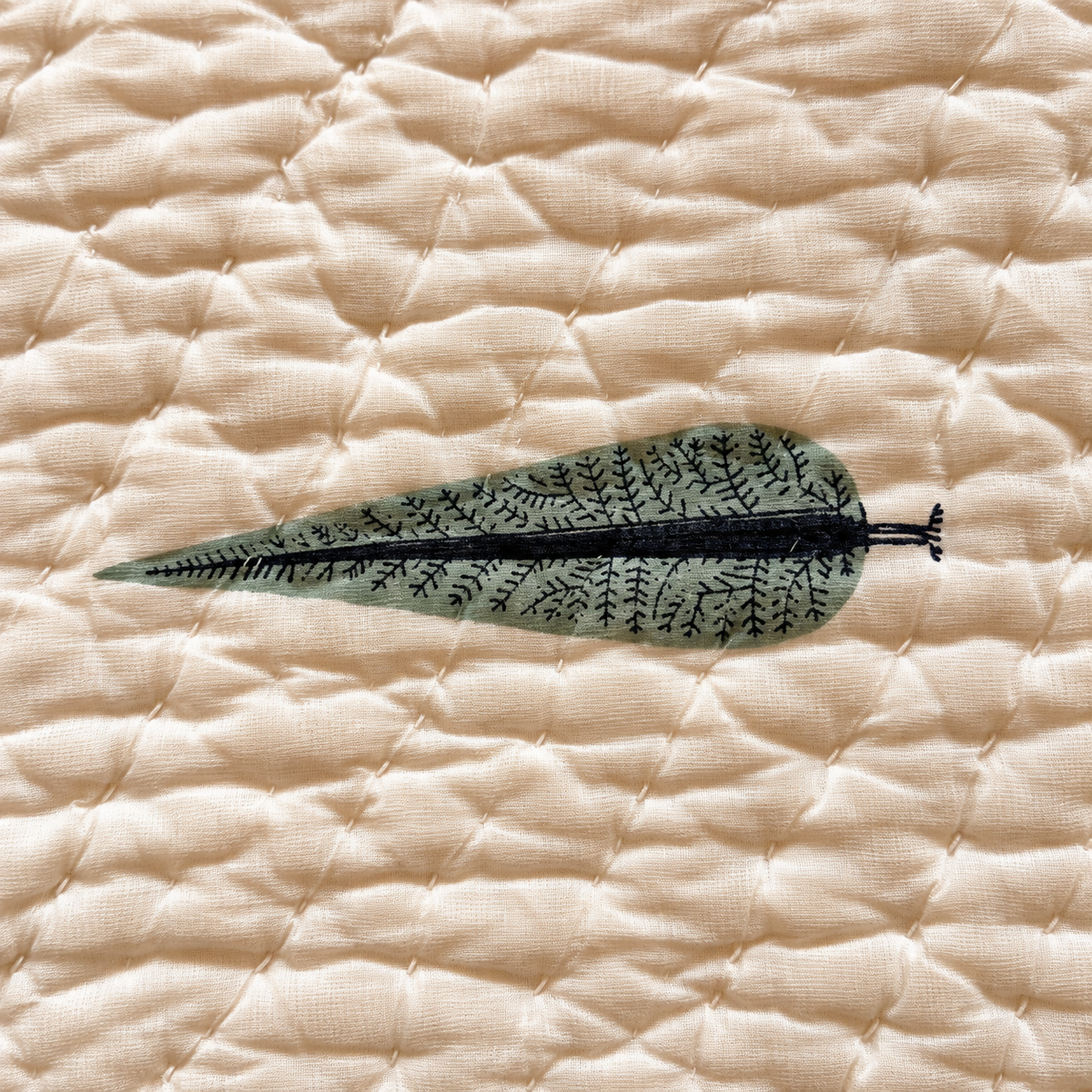 Close-up of Nilgiri quilt sage leaf motif on quilted cotton